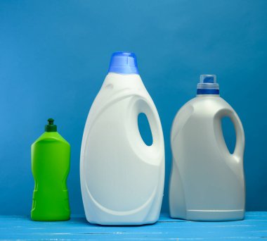 Mavi arka planda deterjanları olan plastik şişeler, kapatın.