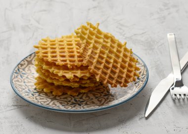 Beyaz bir masada yuvarlak tabakta pişmiş Belçika waffle 'ı yığını, lezzetli bir kahvaltı.
