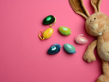 Uzun kulaklı, sevimli, peluş tavşan, dekoratif yumurta, paskalya pembesi arka plan.