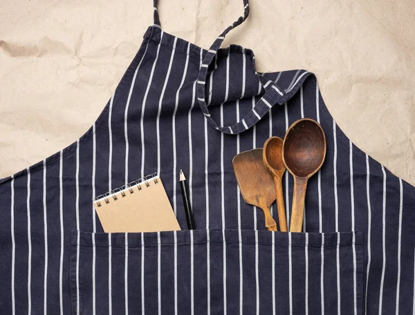blue chef\'s apron, inside a pocket of wooden spoons, top view