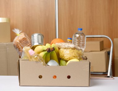 Karton kutu içinde çeşitli ürünler, meyveler, makarna, ayçiçeği yağı ve plastik bir şişede muhafaza. Bağış konsepti