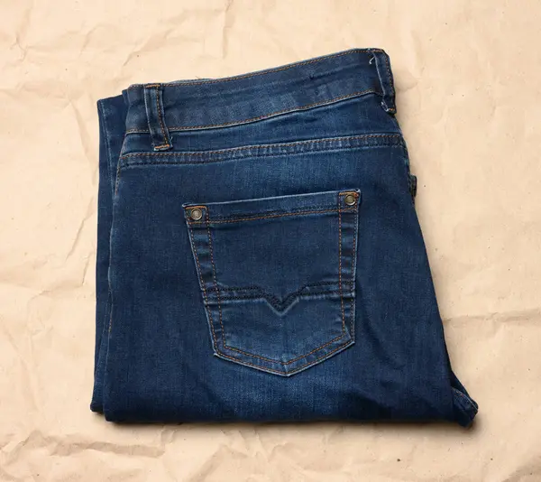 Gefaltete Blaue Männer Jeans Auf Braunem Papierhintergrund Ansicht Von Oben — Stockfoto