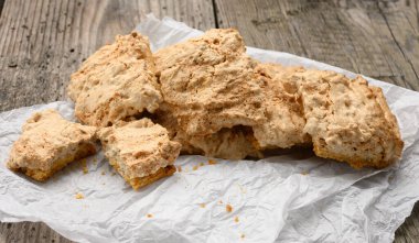 Kare şeklinde kurabiye parçaları bir kağıt parçasına, ahşap gri masaya, parlatmalı kurabiyelere