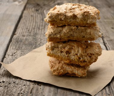 Kare şeklinde kurabiye parçaları bir kağıt parçasına, ahşap gri masaya, kurabiyeleri parlatmaya, kapamaya yatar.