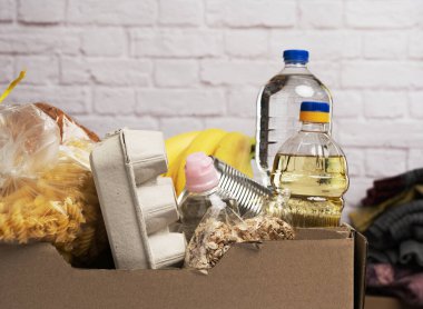 Karton kutu içinde çeşitli ürünler, meyveler, makarna, ayçiçeği yağı ve plastik bir şişede muhafaza. Bağış konsepti
