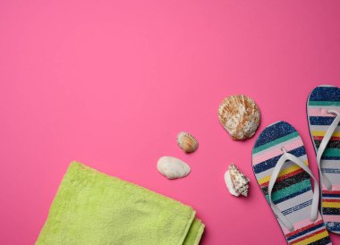 Pembe arka planda kadın terlikleri ve deniz kabuğu, üst manzara.