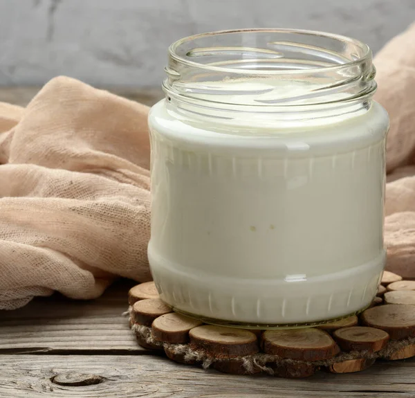 自制酸奶 装在木制桌子上的透明玻璃瓶中 是一种健康的发酵牛奶产品 — 图库照片