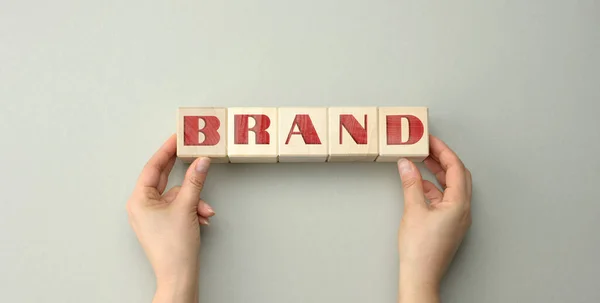 碑文ブランドとグレーの背景に2人の女性の手で木製のブロック ロゴデザイン 企業戦略のブランド信頼の概念 — ストック写真