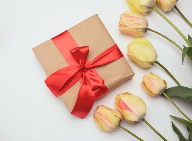 Beyaz arka planda kırmızı hediye kutusu ve sarı laleler, şenlikli arka plan, üst manzara