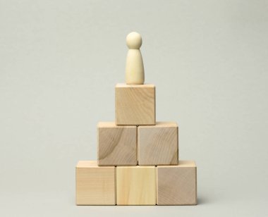 Piramidin tepesindeki tahta bir adam heykeli. Kariyer gelişimi kavramı, hedef başarısı. Kişisel gelişim, şirket başkanı, CEO.