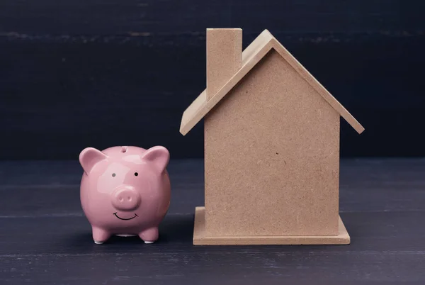 pink ceramic piggy bank and  house on a blue background. Real estate rental, purchase and sale concept. Realtor services