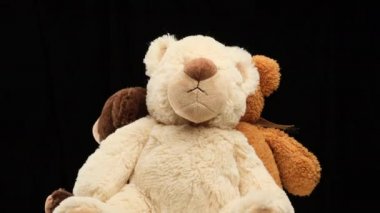 Farklı boyutlarda üç pelüş oyuncak ayı siyah arka planda döner. Çocuk oyuncağı