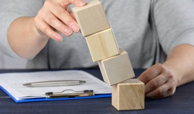 Kadın eli, düşen küpleri masanın üzerinde tutuyor. Yönetici krizi kavramı, şirketi ayakta tutmak, girişimi dengelemek. Geliştirme stratejisi