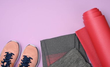 Mor arka planda bir çift pembe spor ayakkabı. Spor aletleri ve eşyalar, düz yatak.
