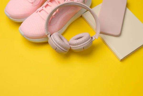 一双粉色运动鞋 无线耳机 智能手机和一个黄色背景的智能手表 运动用的东西和小玩意 — 图库照片