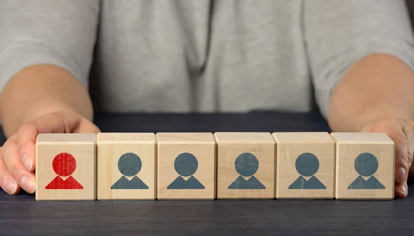 female hands hold wooden cubes with figurines. Employee search concept, staff recruitment. Selection of talented and unique employees for career advancement