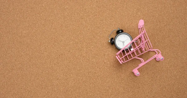 Pink Shopping Cart Black Alarm Clock Brown Background Time Money — Zdjęcie stockowe