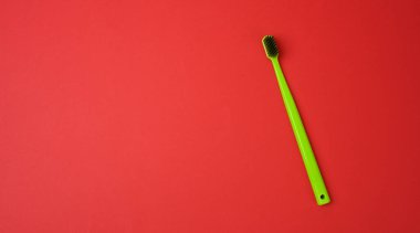 green plastic toothbrush isolated on a red background, hygiene product, copy space 