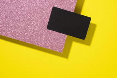 blank black rectangular business card on a creative background from sheets of paper with shadow, yellow sheets, flat lay
