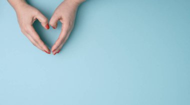 two female hands folded in the shape of a heart on a blue background. Gratitude and kindness concept, banner, copy space