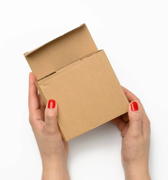 两只雌性手拿着一个方形盒子 盒子是用褐色波纹纸板做的 背景是白色的 — 图库照片