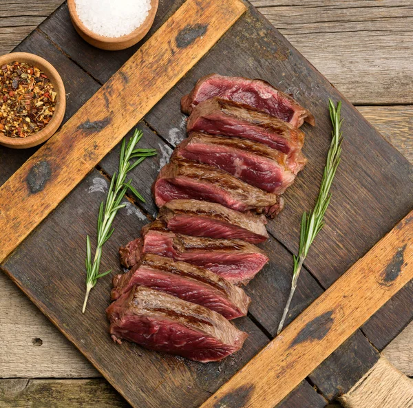 经典的牛肉牛排 未煮熟的肉 在外面煎 里面是红色的 有红色的果汁 切碎在木板上 准备得很少 — 图库照片