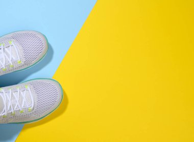 Mavi sarı arka planda bağcıkları olan beyaz kadın ayakkabıları, üst manzara, kopyalama alanı