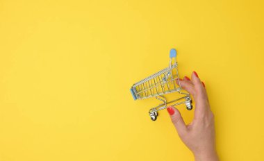 Kirli eller sarı arka planda boş metal bir tramvayı tutuyor. Satış konsepti, mevsimlik indirimler, fotokopi alanı