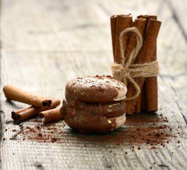 Fırında çikolatalı makaron ve gri arka planda bağlanmış tarçın çubukları.
