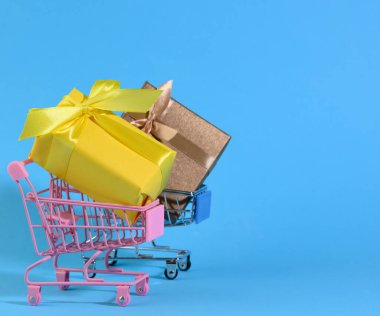 Açık mavi arka planda minyatür metal bir tramvayda ipek fiyonklu sarı hediye kutusu. Parti Arkaplanı, Sürpriz, Mevsimlik Satış