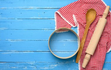 Tahta merdane, yuvarlak ahşap elek mavi arka planda, kırmızı peçete, üst manzara