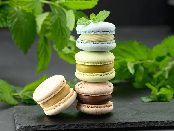 Pile Macarons Multicolores Sur Fond Noir Derrière Des Brins Verts — Photo