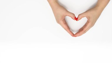 Beyaz arka planda kalp şeklinde katlanmış iki kadın eli. Minnettarlık ve nezaket kavramı, kopyalama alanı