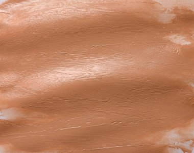 Beyaz arka planda bej rengi sıvı kapatıcı yüz kremi örnekleri var. Sıvı sıkılmış.