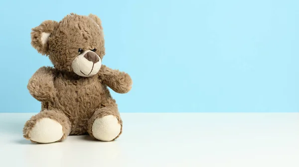 Lindo Oso Peluche Marrón Sentado Una Mesa Blanca Fondo Azul —  Fotos de Stock