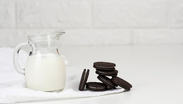 Volle Glaskaraffe Milch Und Ein Stapel Schokoladenkekse Auf Einem Weißen — Stockfoto