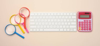 Beyaz kablosuz klavye ve bej arka planda büyüteç, bütçe analiz konsepti, tasarruf. Çevrimiçi alışveriş, üst manzara