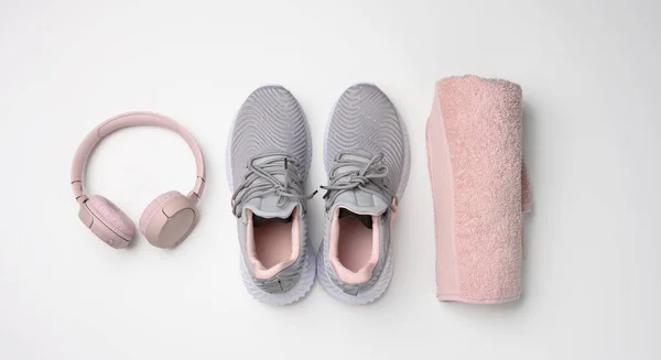 一双灰色的纺织品运动鞋 无线耳机和一条白色背景的粉色纺织品毛巾 准备参加体育运动 — 图库照片