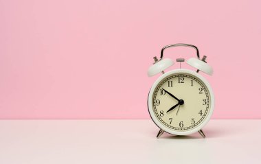 Beyaz bir masanın üzerindeki beyaz metal çalar saat, sabah 8 'e 10 kala, boşluğu kopyala