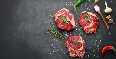 Biberiyeli çiğ sığır pirzolası, siyah bir masada kekik, üst görünüm, kopyalama alanı