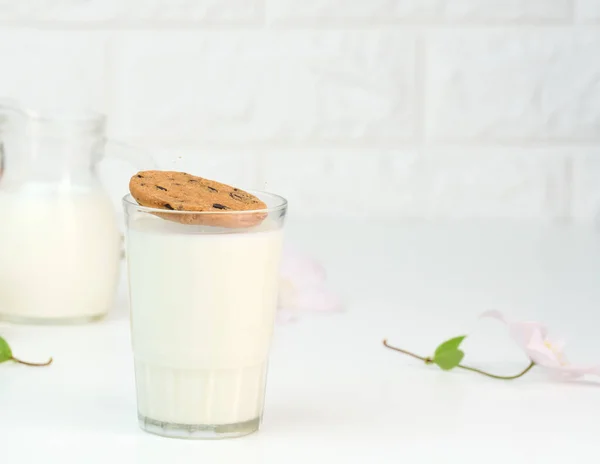 Bicchiere Pieno Latte Biscotto Rotondo Vola Nel Bicchiere Tavolo Bianco — Foto Stock
