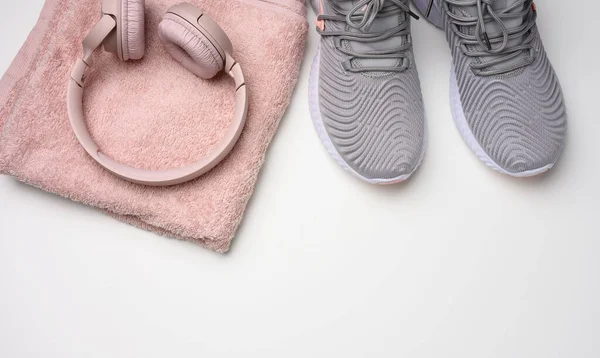 Par Grå Textila Sneakers Trådlösa Hörlurar Och Textil Rosa Handduk — Stockfoto