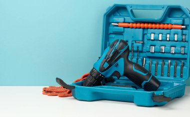 Beyaz arkaplanda kablosuz matkap, matkap ve tornavida seti olan plastik kutu, boşluğu kopyala