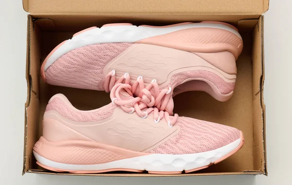 Par Rosa Textila Sneakers Öppen Brun Papperslåda Ett Vitt Bord — Stockfoto