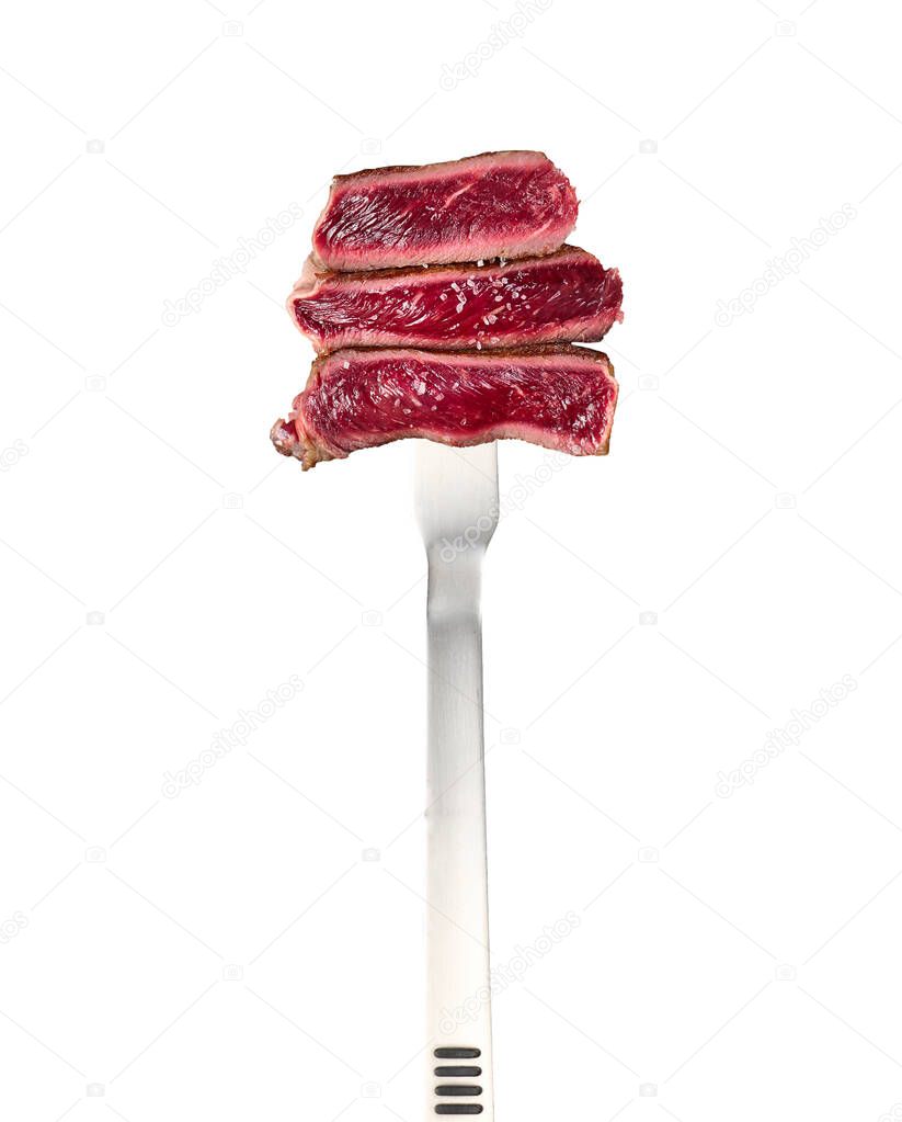 fried ribeye pieces strung on a large metal fork and isolated on a white background, the degree of doneness rare