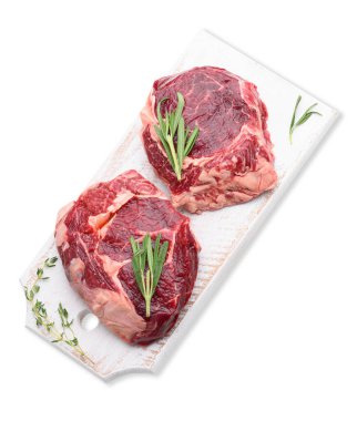 Biberiyeli çiğ sığır pirzolası, beyaz ahşap kesme tahtasında kekik, üst manzara. Gıda beyaz arkaplanda izole