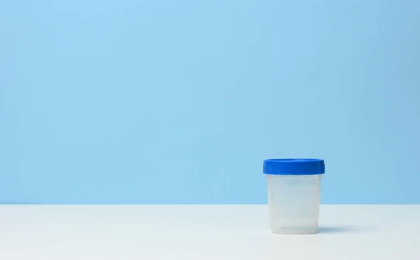 empty plastic container for the collection of analyzes on a white table, blue background, copy space