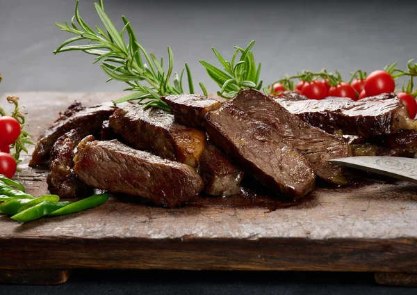 Kızarmış sığır pirzolası parçalanmış. Eskimiş kahverengi bir kesim tahtasıyla, nadir bulunan bir eşarpla. İştah açıcı biftek. 