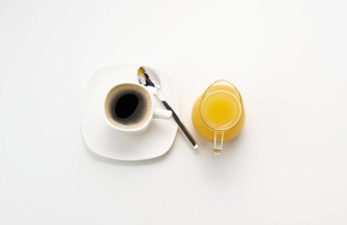 Şeffaf bir sürahide taze sıkılmış meyve suyu, beyaz bir masada bir fincan kahve, bal ve yulaf ezmesi. Sabah kahvaltısı, üst manzara.