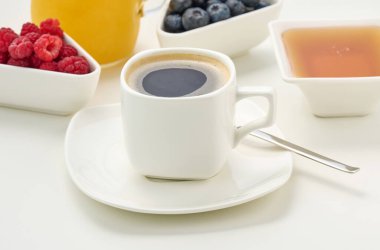 Siyah kahveli beyaz seramik bardak beyaz bir masada duruyor, kahvaltı...